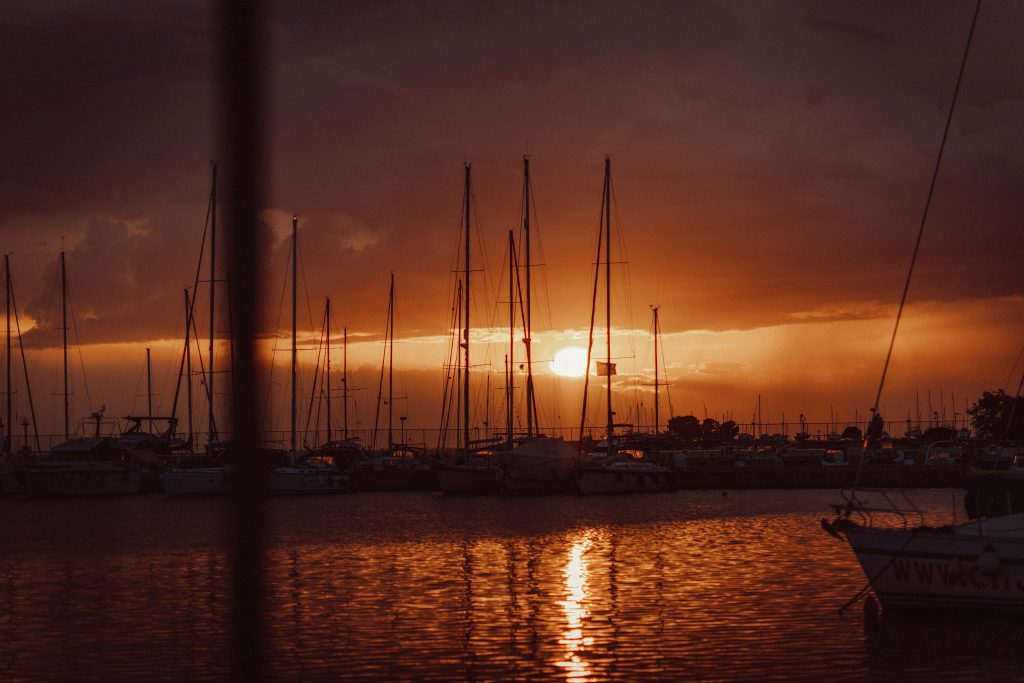 Sailboats moored at sunset in a calm marina
