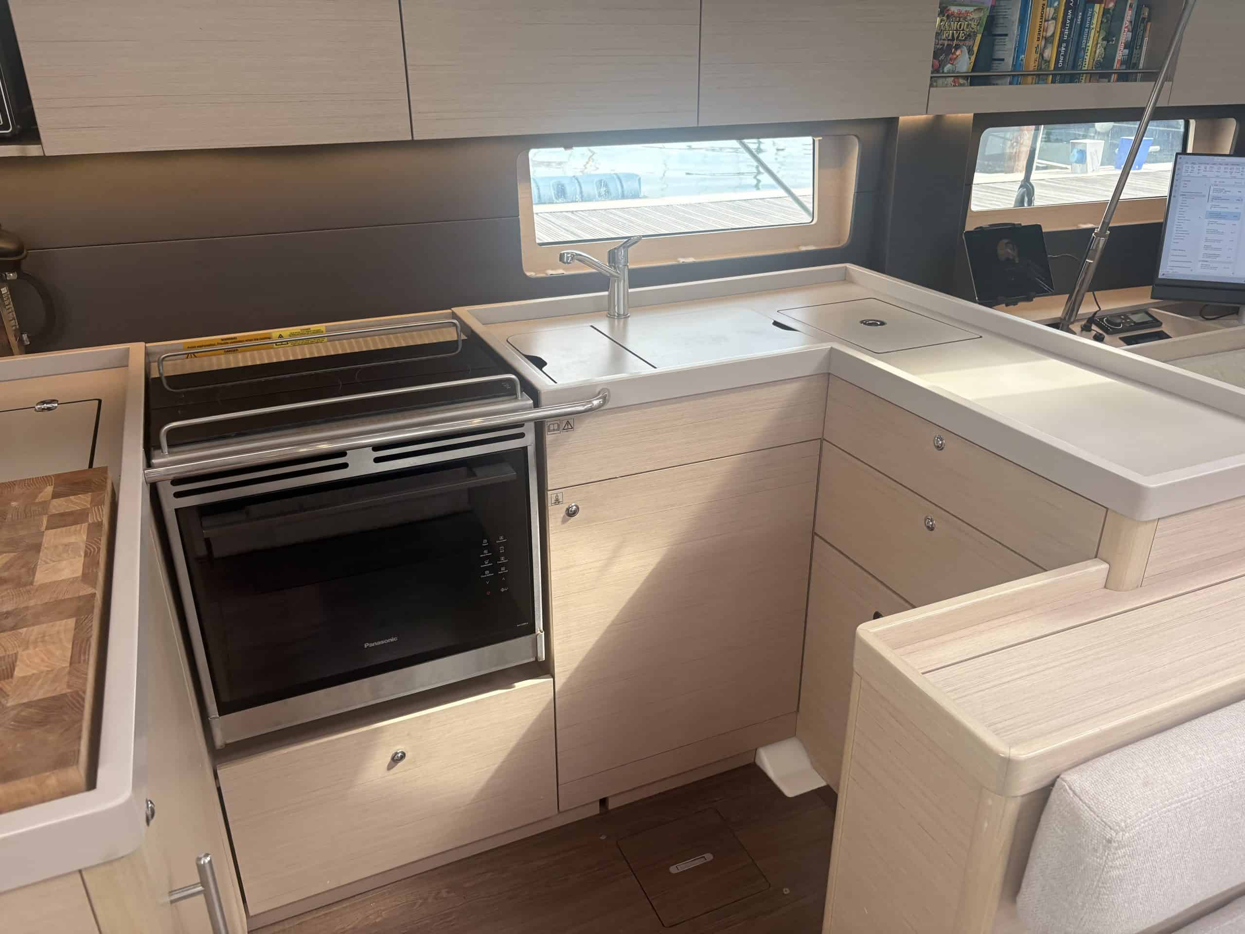 Wider view of the Curio electric oven and induction hob installed in the light-oak galley of a Beneteau Oceanis 51.1, beside the sink and saloon window
